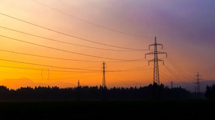 Electric lines along mountains at sunset