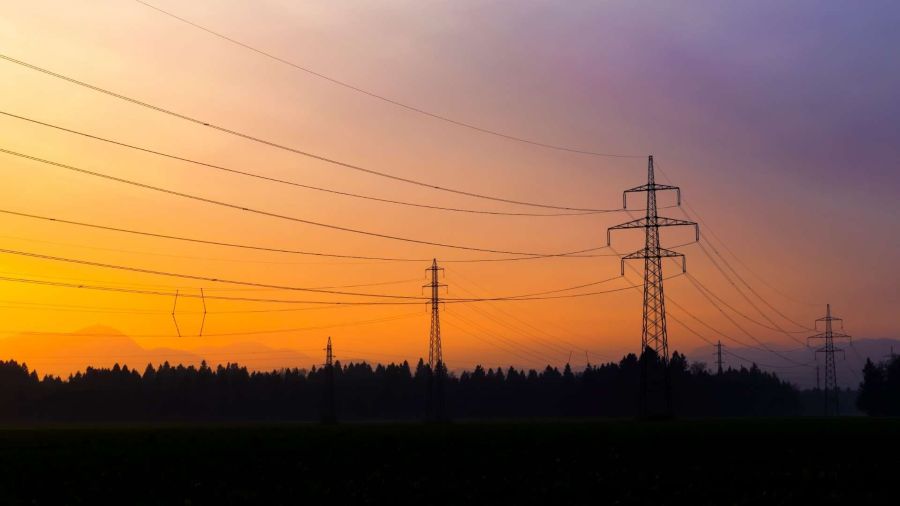 Electric lines along mountains at sunset