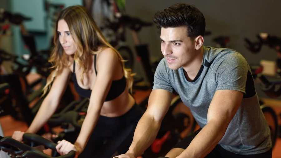 Two people exercising on stationary bikes in a gym