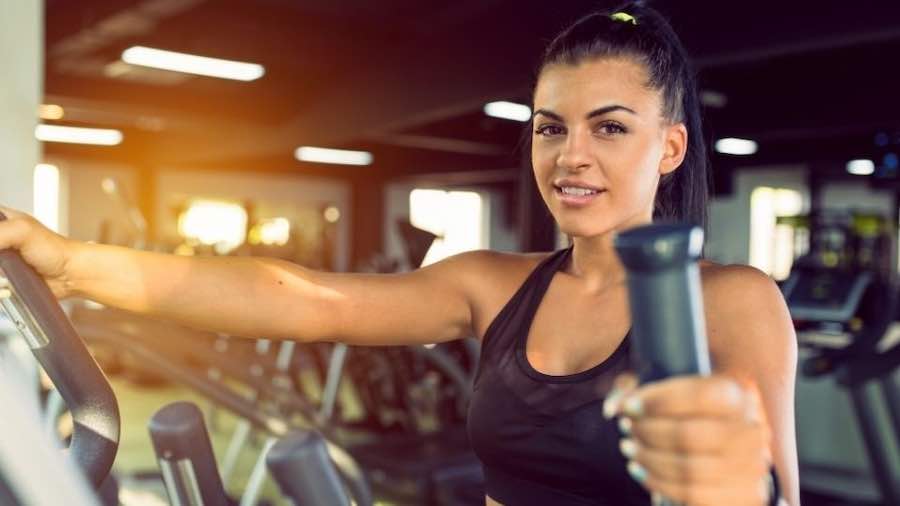 Female focusing on an upper-body workout on an elliptical trainer