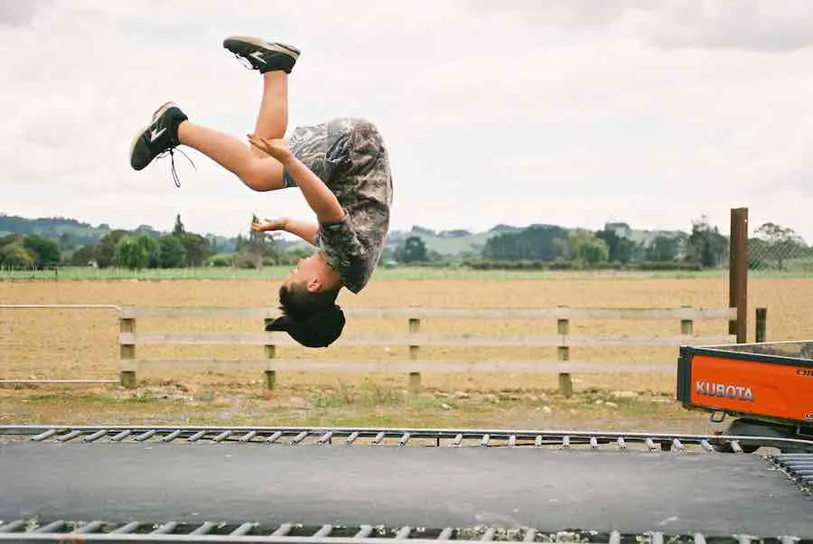 Boy doing back flip on trampoline mat