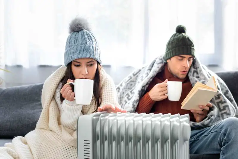 Couple reading next to an oil space heater