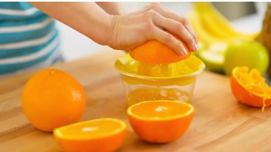 Someone manually juicing an orange