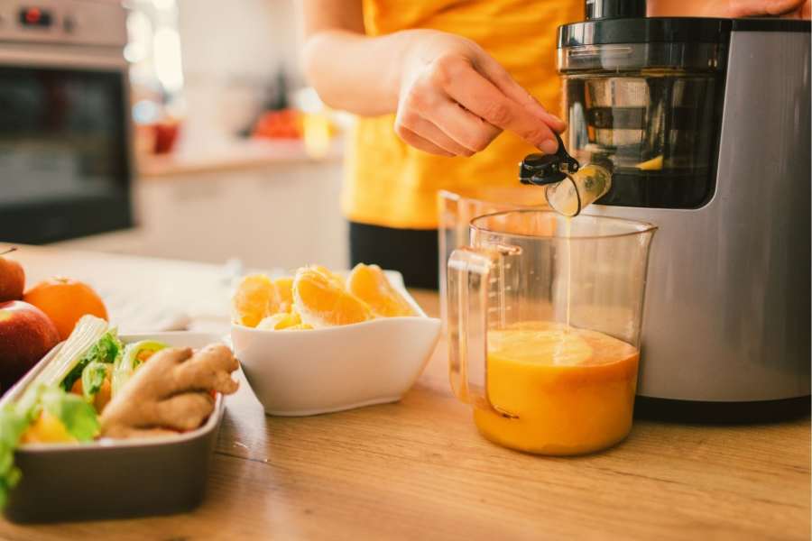 Person making fresh juice using a cold press juicer 