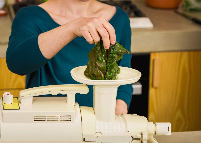 Woman juicing leafy greens using a slow juicer