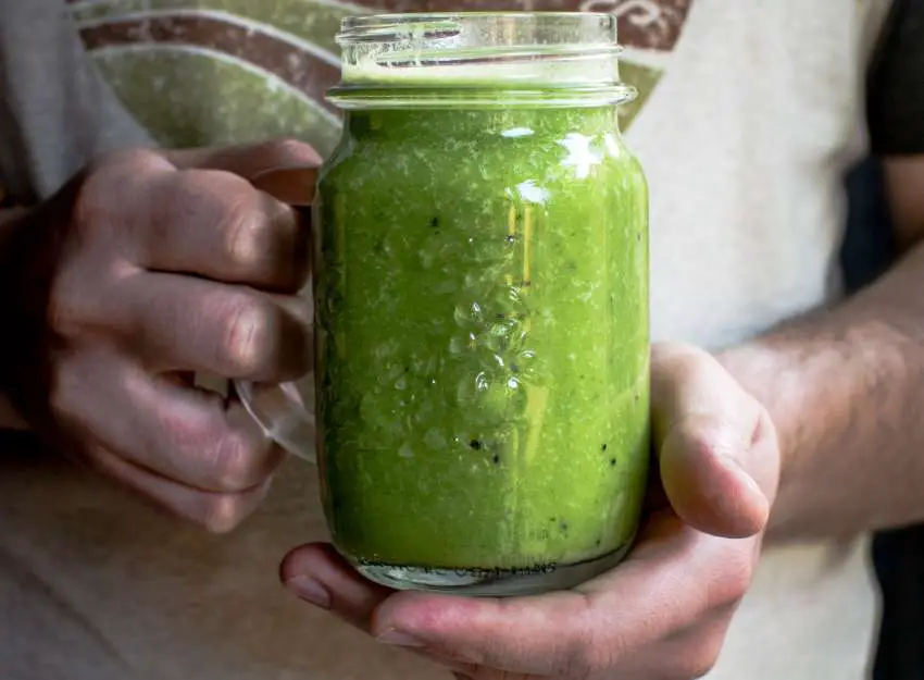Person holding a mason jar of fresh green juice