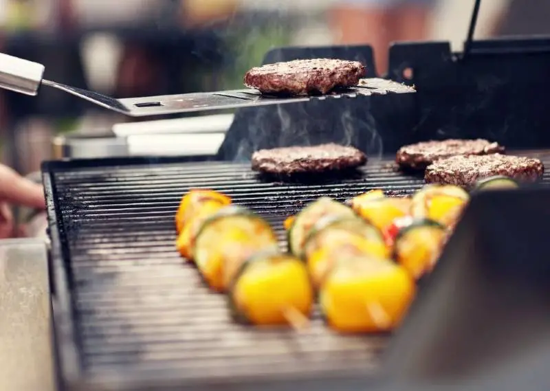 Meat and veggies cooking on a small gas grill 