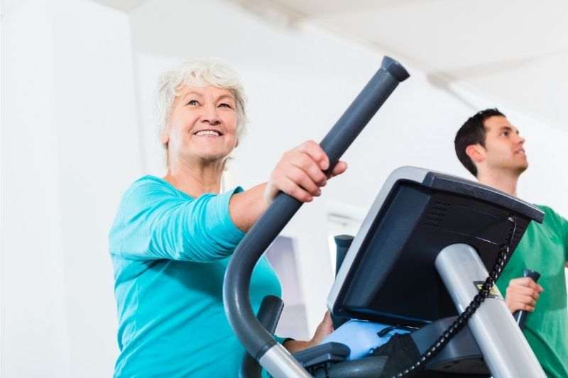 A senior lady doing cardio on an elliptical cross trainer 