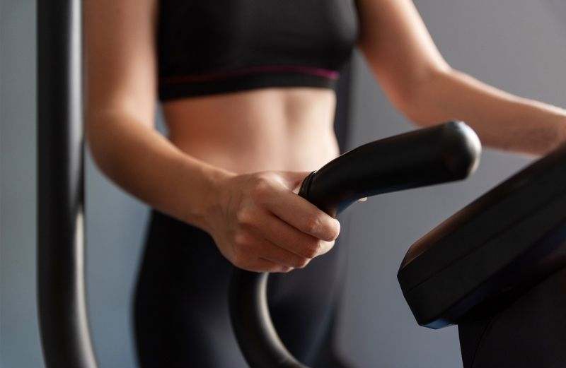 A close-up of a woman's hands holding the elliptical handles 