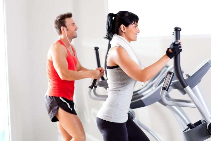 A couple of sports enthusiasts doing cardio on elliptical machines 