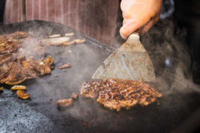 Pieces of meet and mushrooms roasting on a griddle 