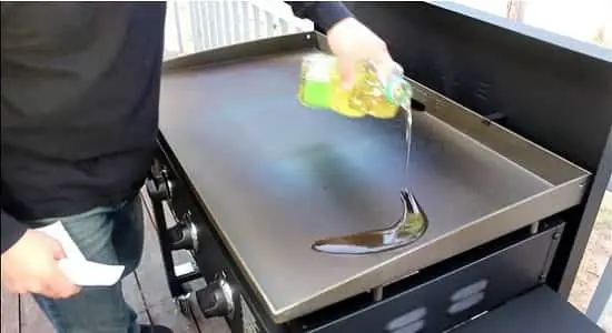 Man pouring vegetable oil on a blackstone griddle 