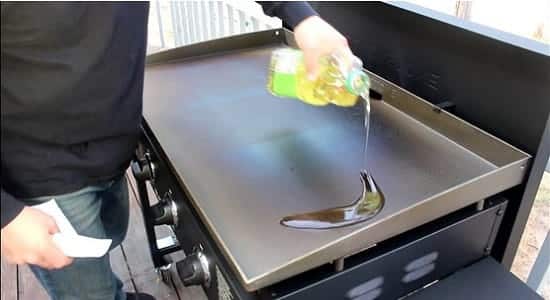 Man pouring vegetable oil on a blackstone griddle 