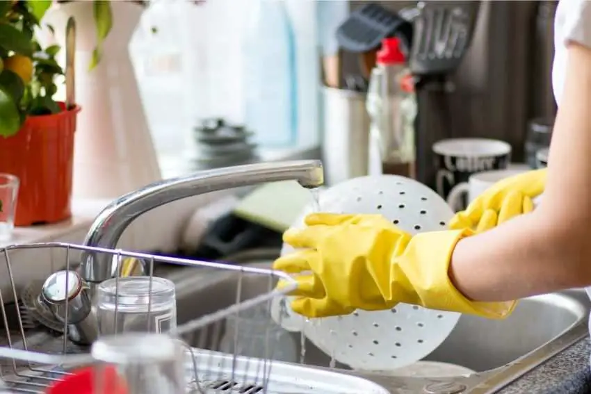 A person washing dishes and juicer parts 