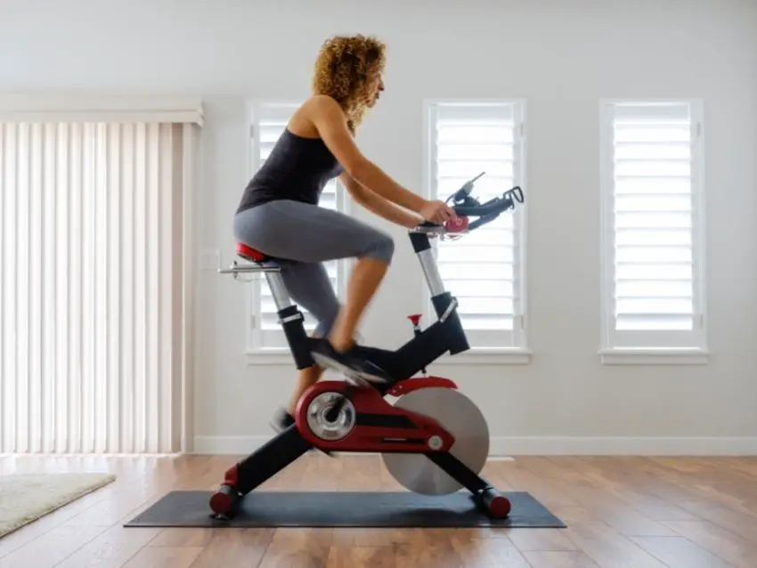 A woman exercising on a magnetic spin bike at home.