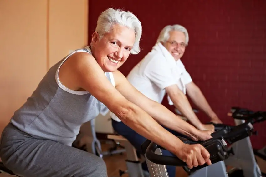 A senior couple exercising on spin bikes at home