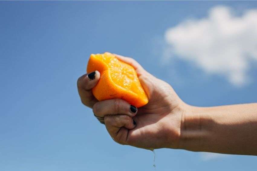 A close-up of a hand squeezing an orange 