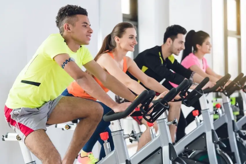 A group of four young people cycling together on spin bikes