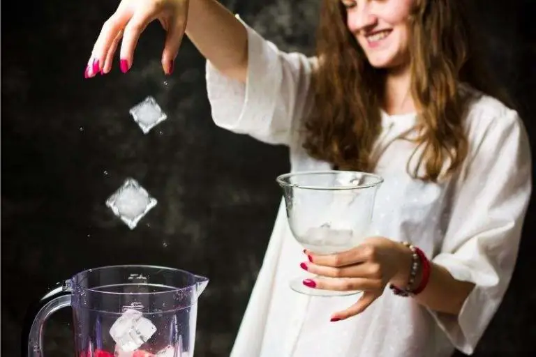 woman adding ice to a blender used for frozen drinks