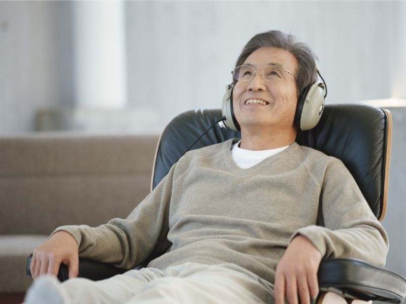 A senior man relaxing in a recliner, listening to music