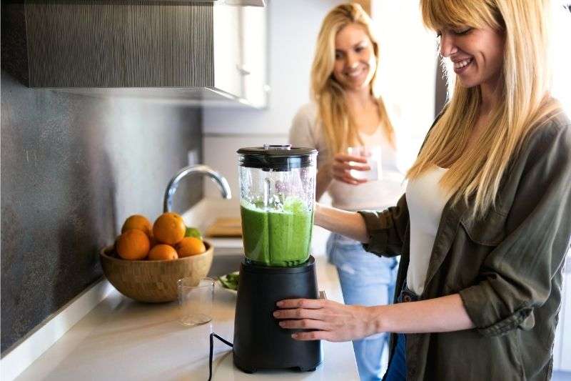 A couple of young women making green juice