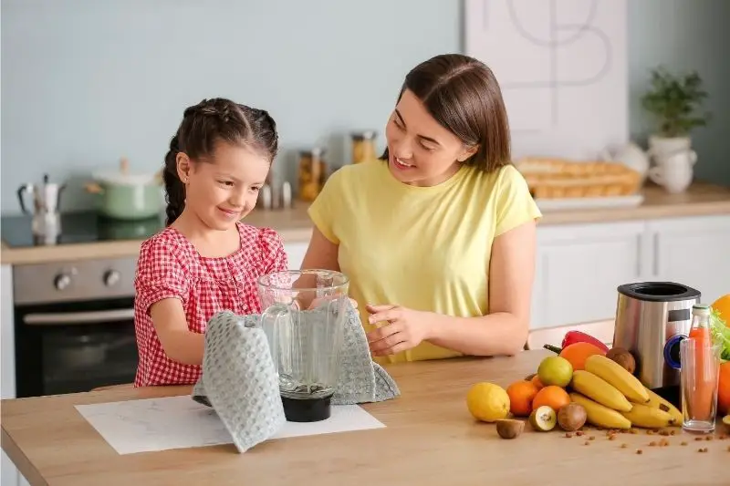 A woman and a girl finishing up the blender cleaning process