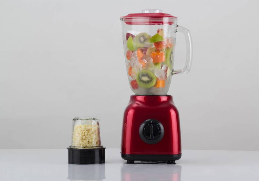 A red blender full of fruit sitting on the counter 