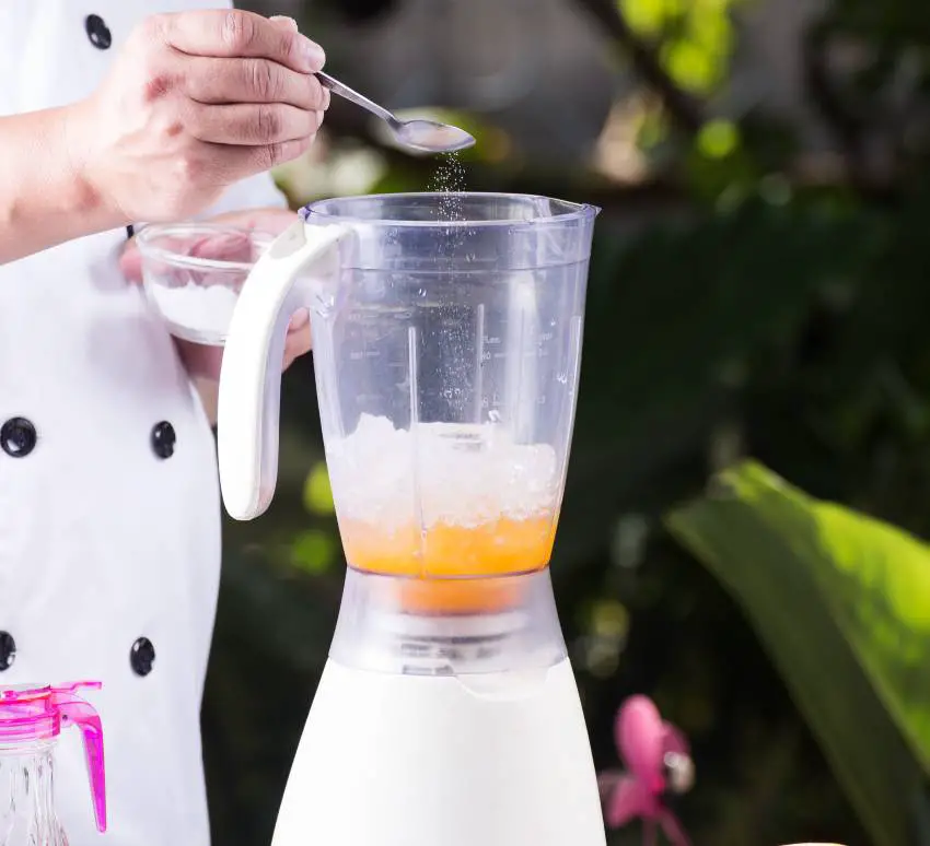 A cheff putting spice onto a blender 