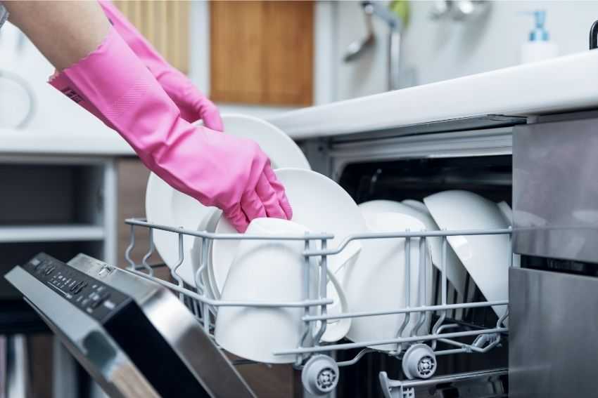 A person working on unloading the dishwasher