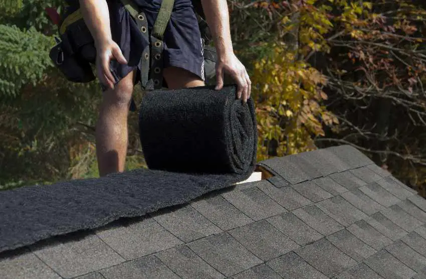 A person installing ridge vent in a roll onto a roof