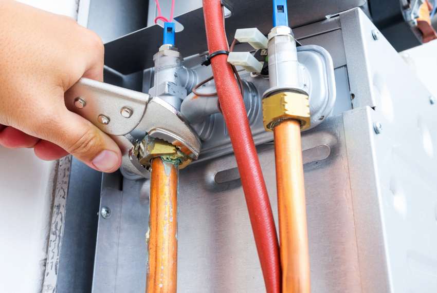 A person installing water heater pipes