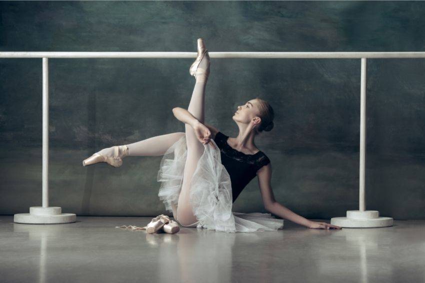 A ballerina posing in front of a ballet barre