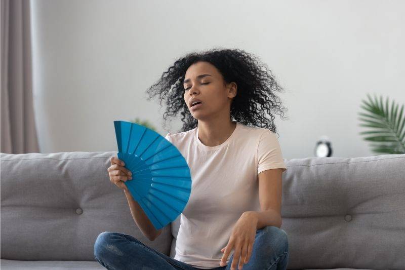 A young woman cooling herself with a hand fan 