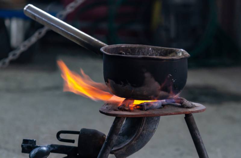 A camping pot heating up on a propane burner 