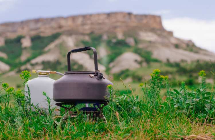 A peopane burner nex to a tank on camping ground