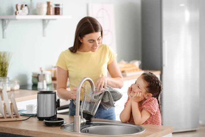 Mother and little daughter washing a blender manualy 