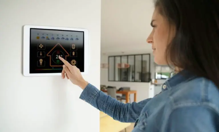 woman adjusting thermostat to select emergency heat