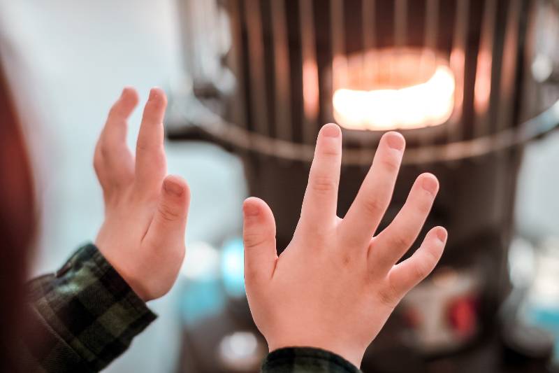 A child warming up next to a kerosene heater