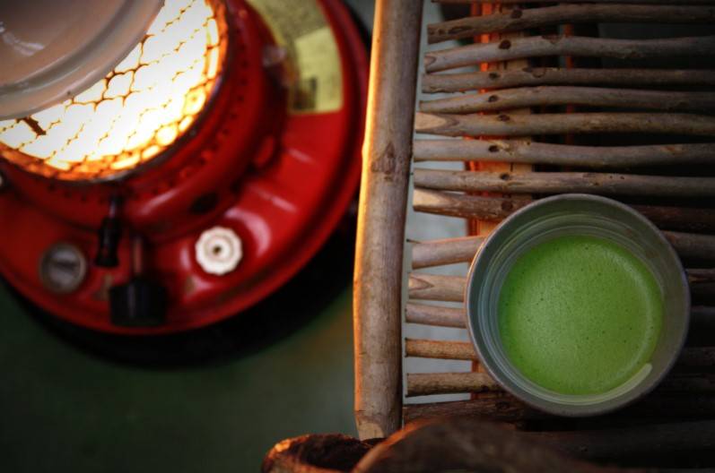 A mug of macha tea next to a kerosene heater 