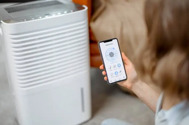 A woman controliing an air purifier unit via a smartphone app