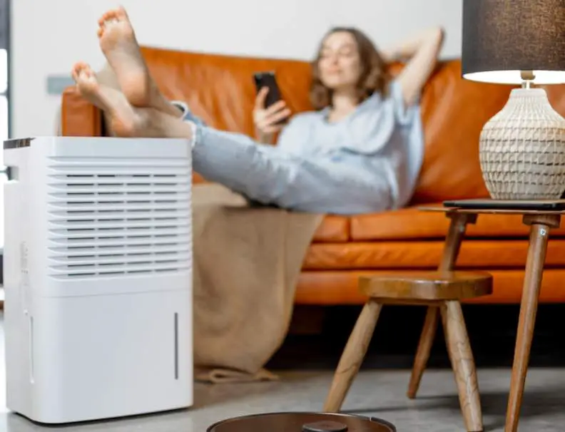 A young woman relaxing in her room next to a dehumidifier