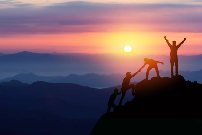 the team climbing to the top of a mountain and celebrating